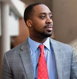 A man in a suit and tie is standing in a hallway.