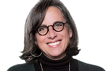 A woman wearing glasses and a black turtleneck is smiling.