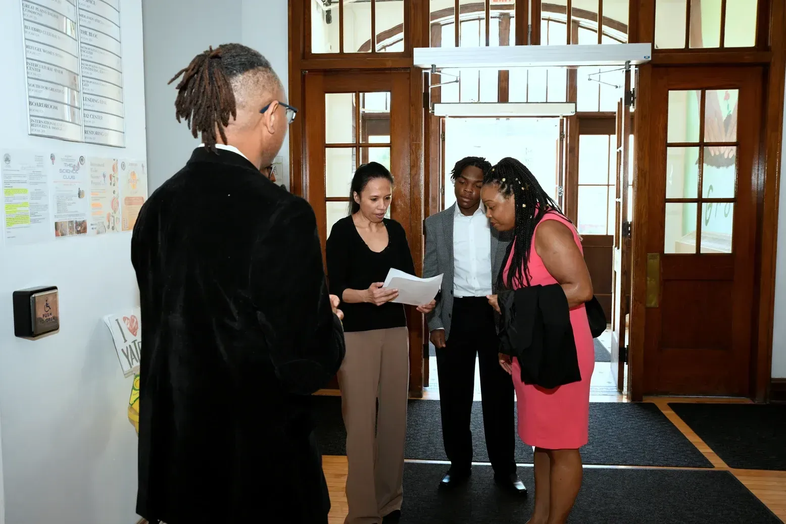 A group of people are standing in a hallway talking to each other