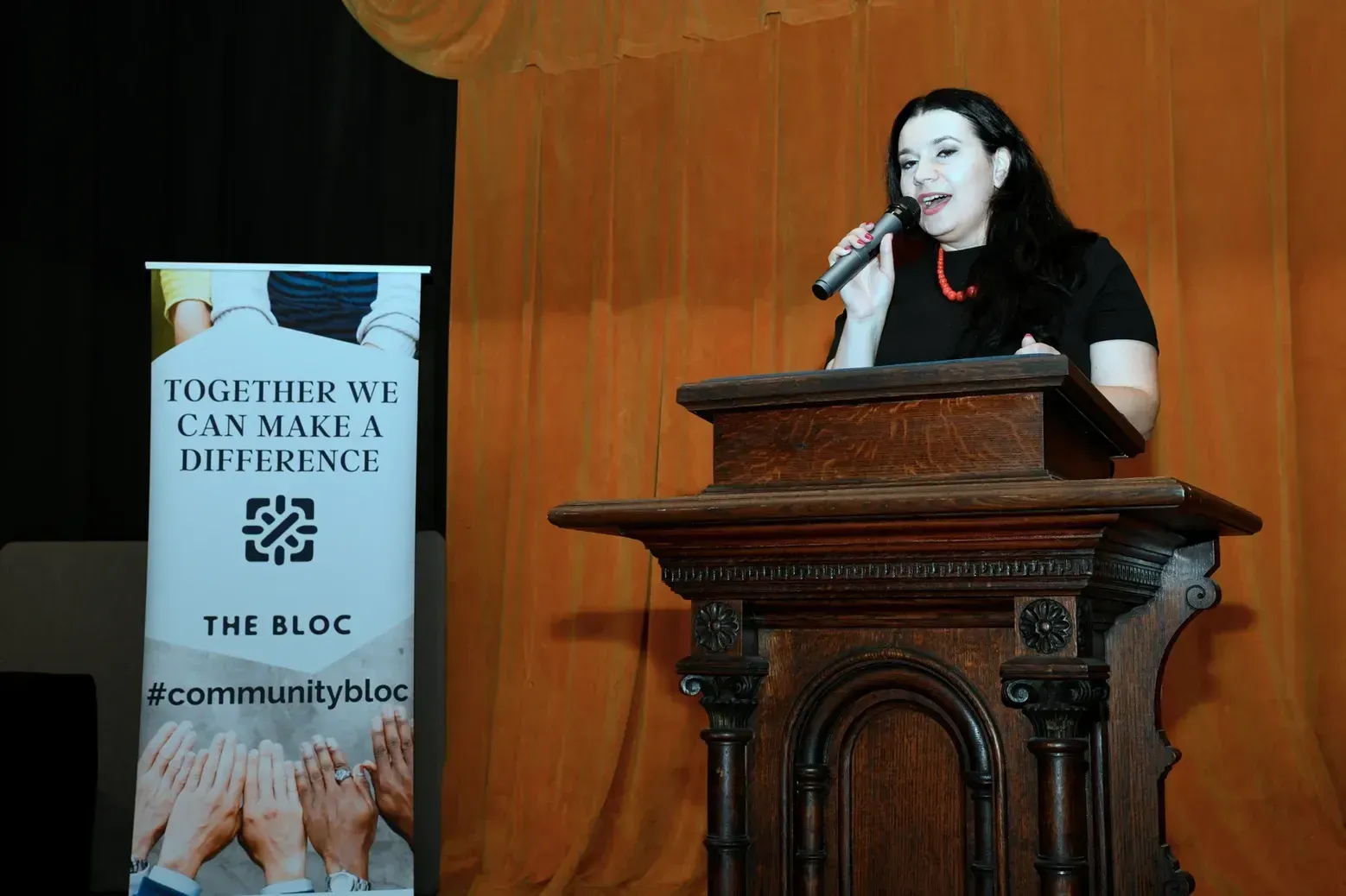 A woman is standing at a podium speaking into a microphone.