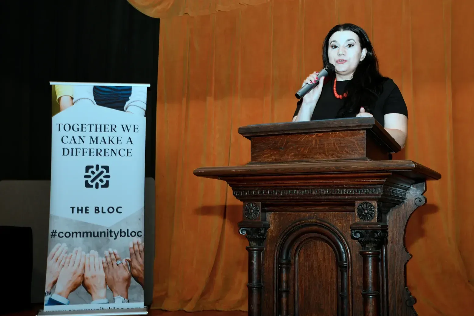 A woman is standing at a podium holding a microphone.