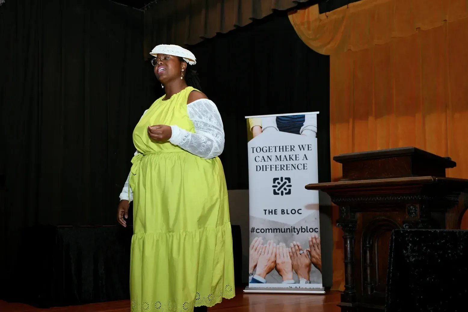 A woman in a yellow dress is standing in front of a sign that says 