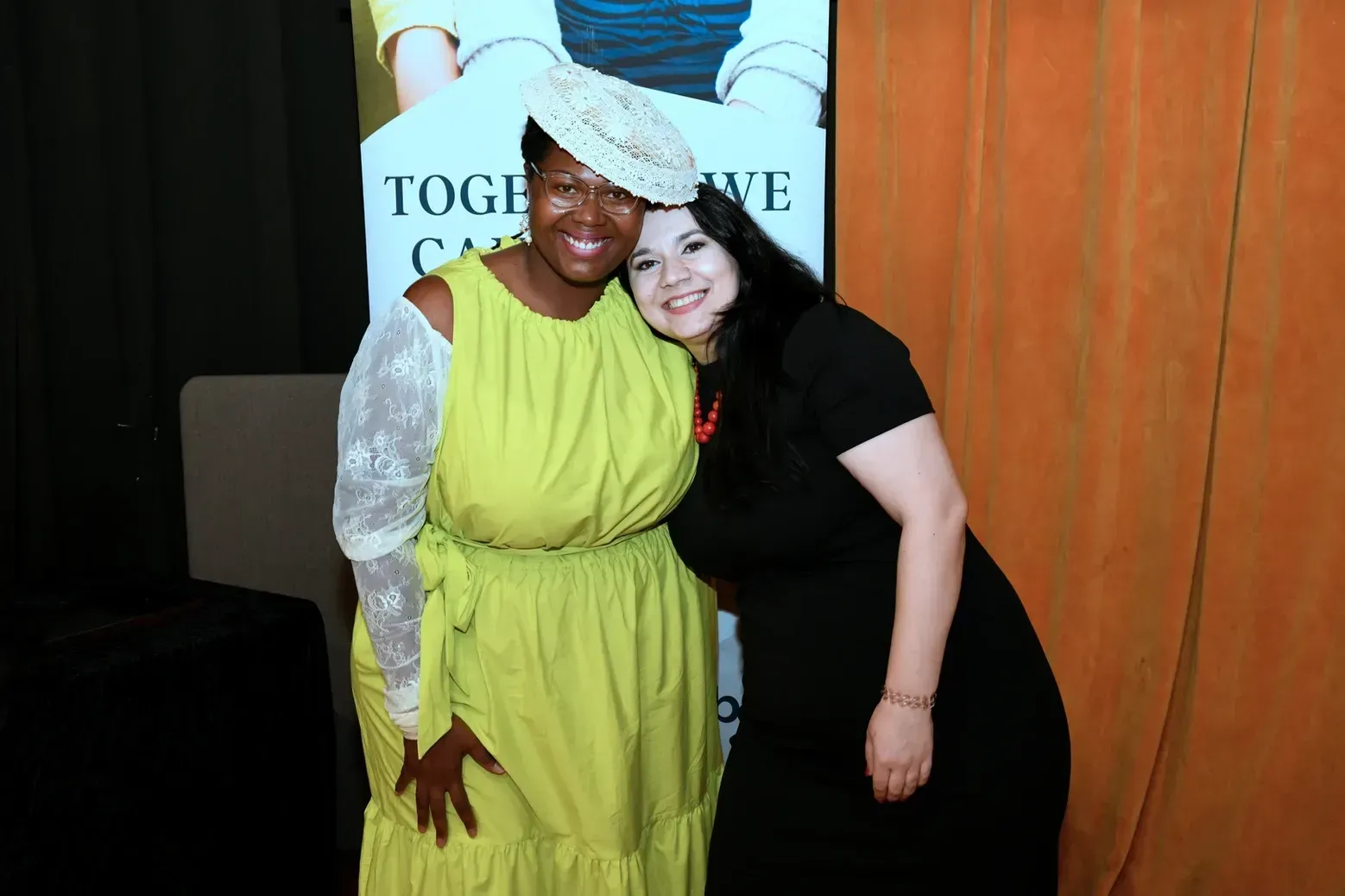 Two women are posing for a picture together and one is wearing a yellow dress.