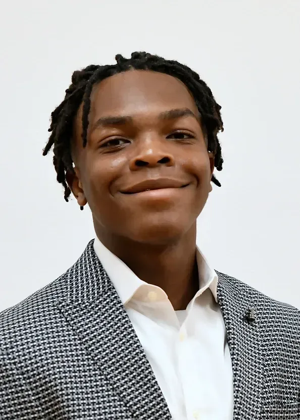 A young man in a suit and white shirt is smiling for the camera.
