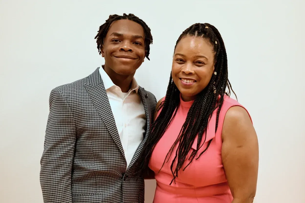 A man in a suit and a woman in a pink dress are posing for a picture.