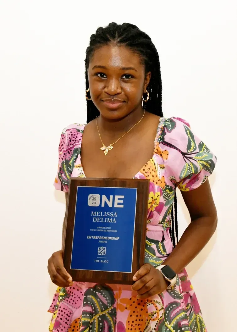A woman in a pink dress is holding a plaque that says one