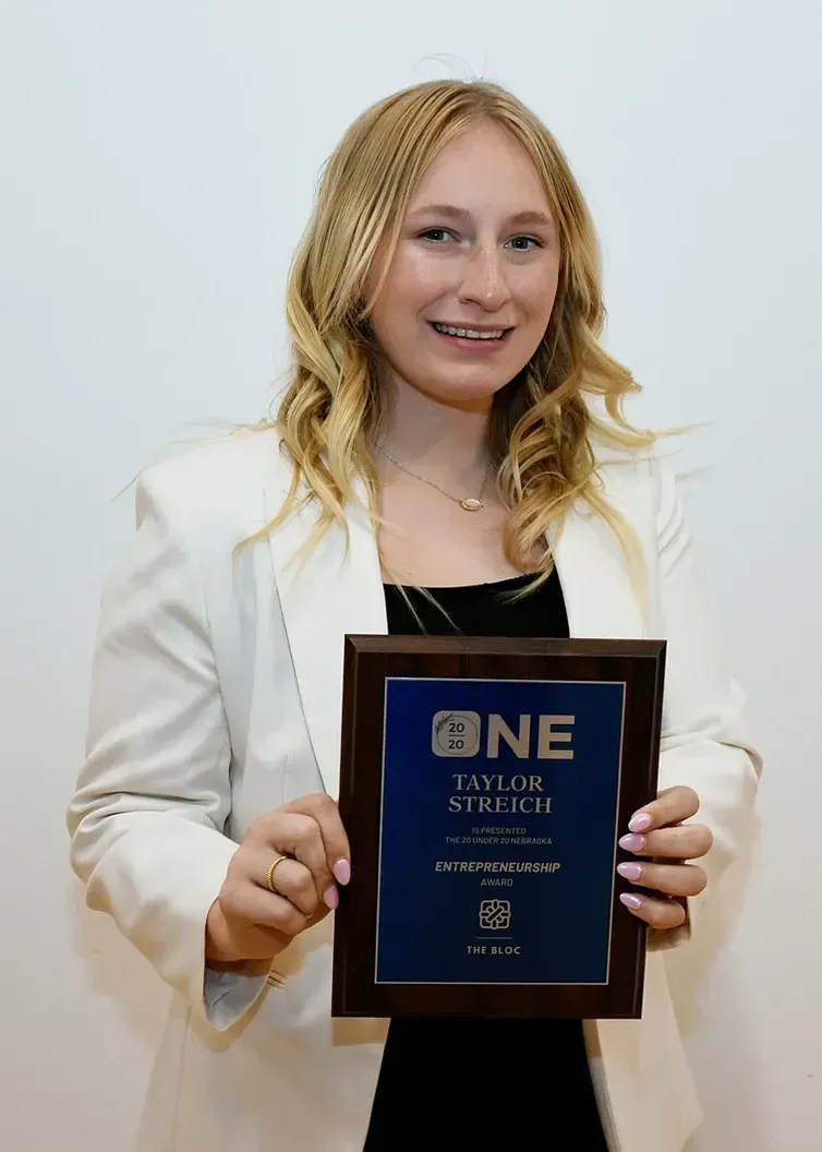 A woman in a white jacket is holding a plaque that says one