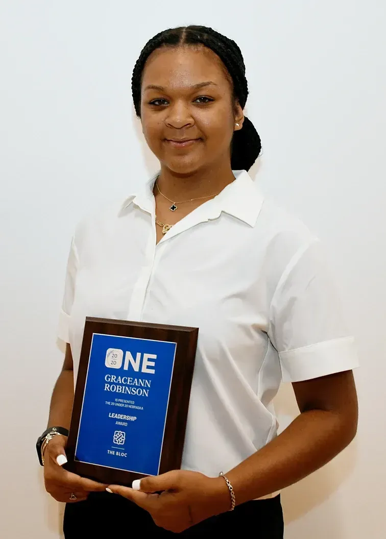 A woman in a white shirt is holding a plaque that says one