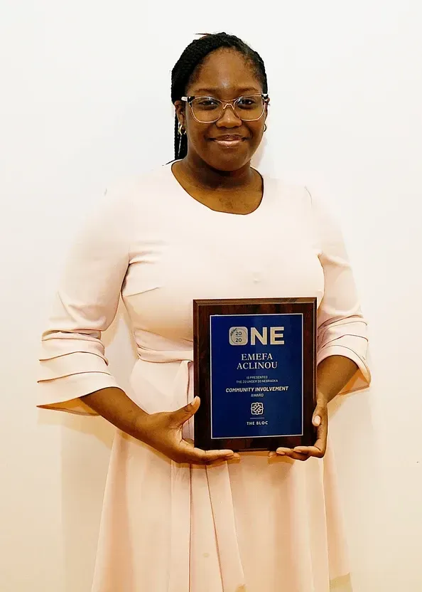 A woman in a pink dress is holding a plaque.
