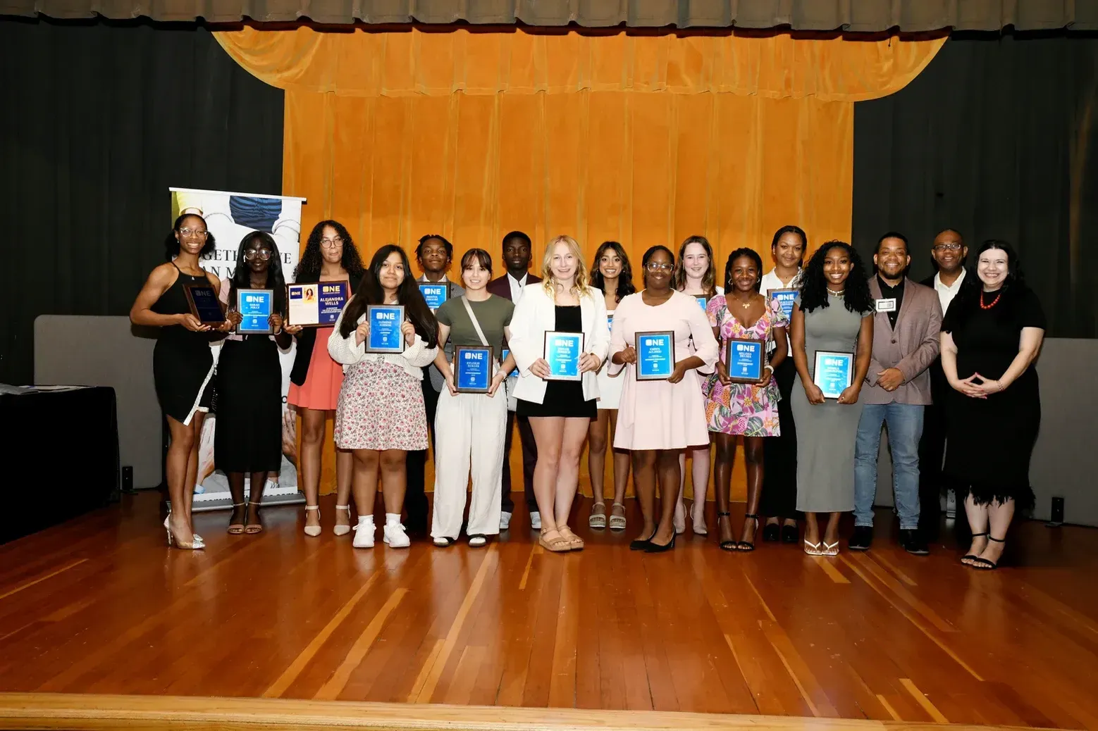 A group of people standing on a stage holding plaques