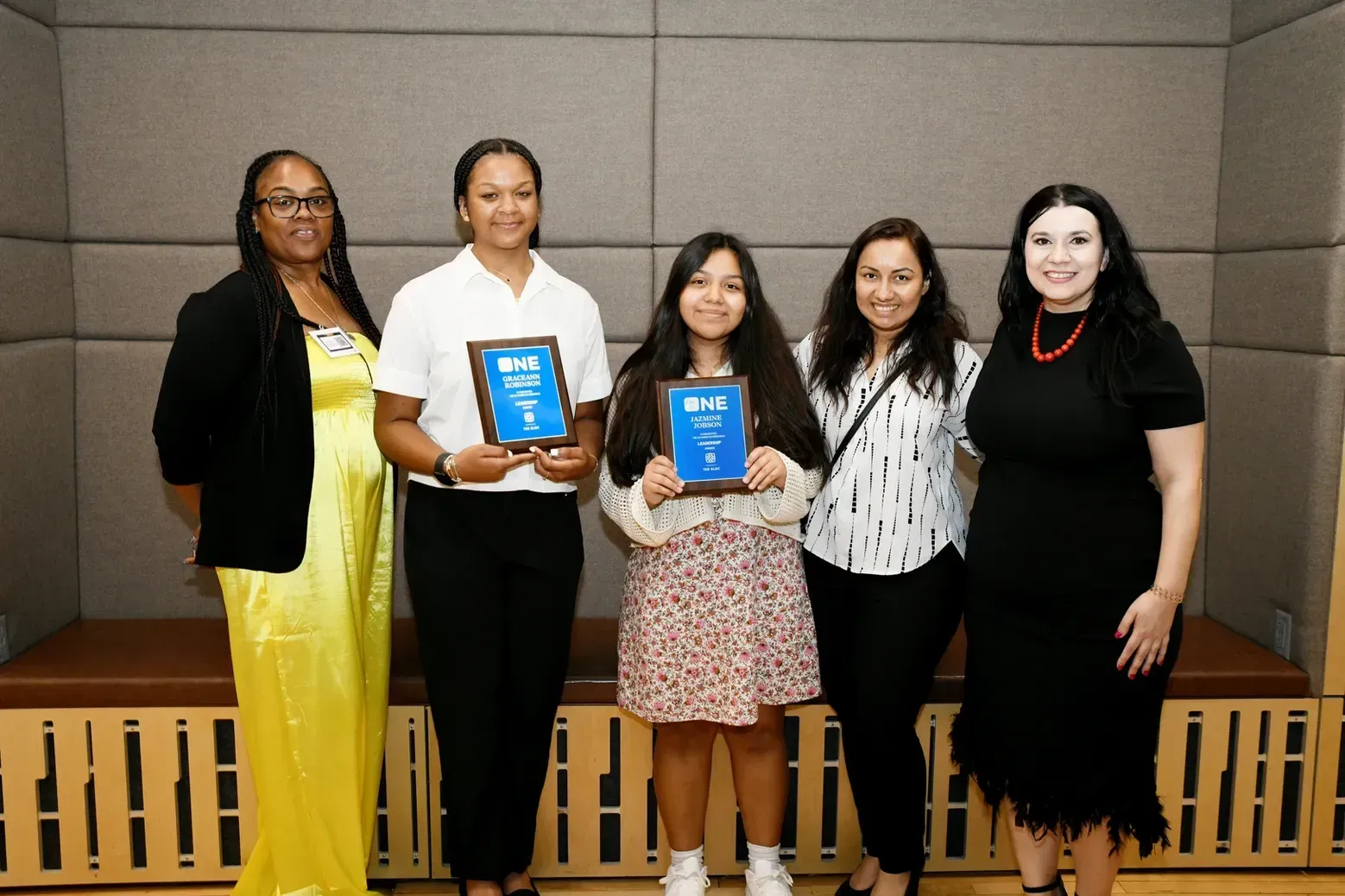 A group of women standing next to each other holding plaques.