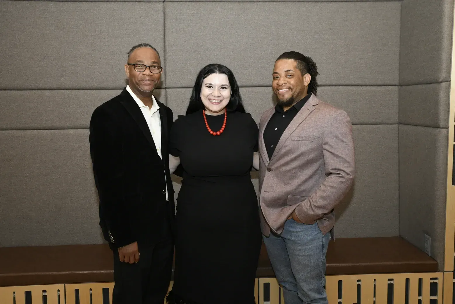 Three people are posing for a picture together in a room.