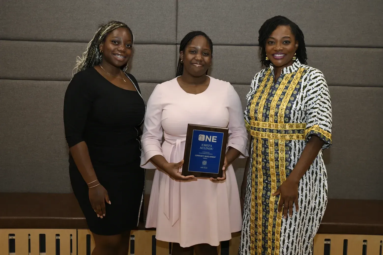 Three women are standing next to each other holding a plaque.