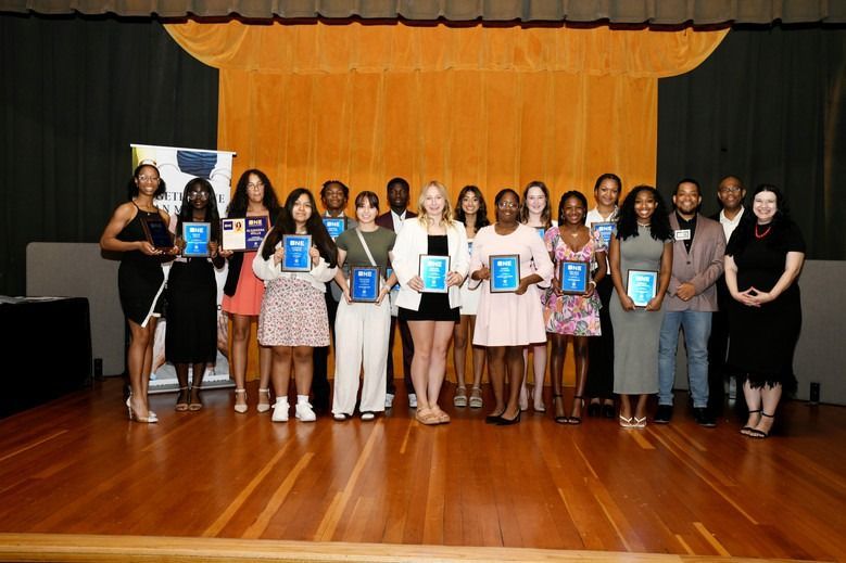 A group of people standing on a stage holding plaques.