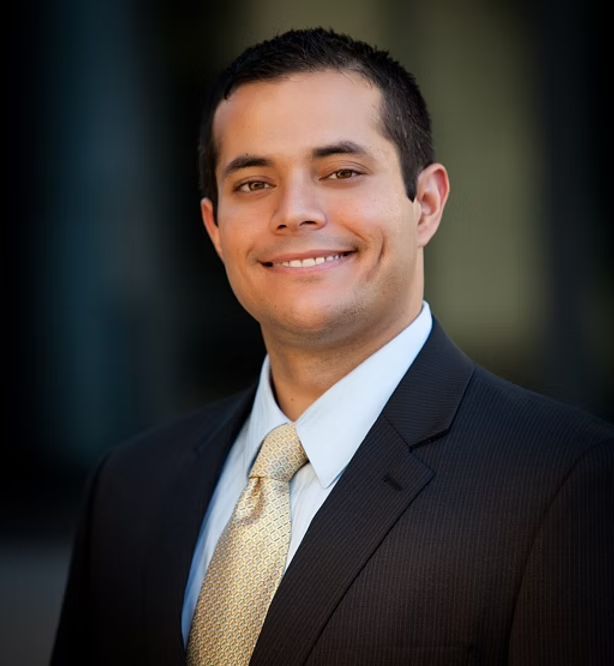 A man in a suit and tie is smiling for the camera