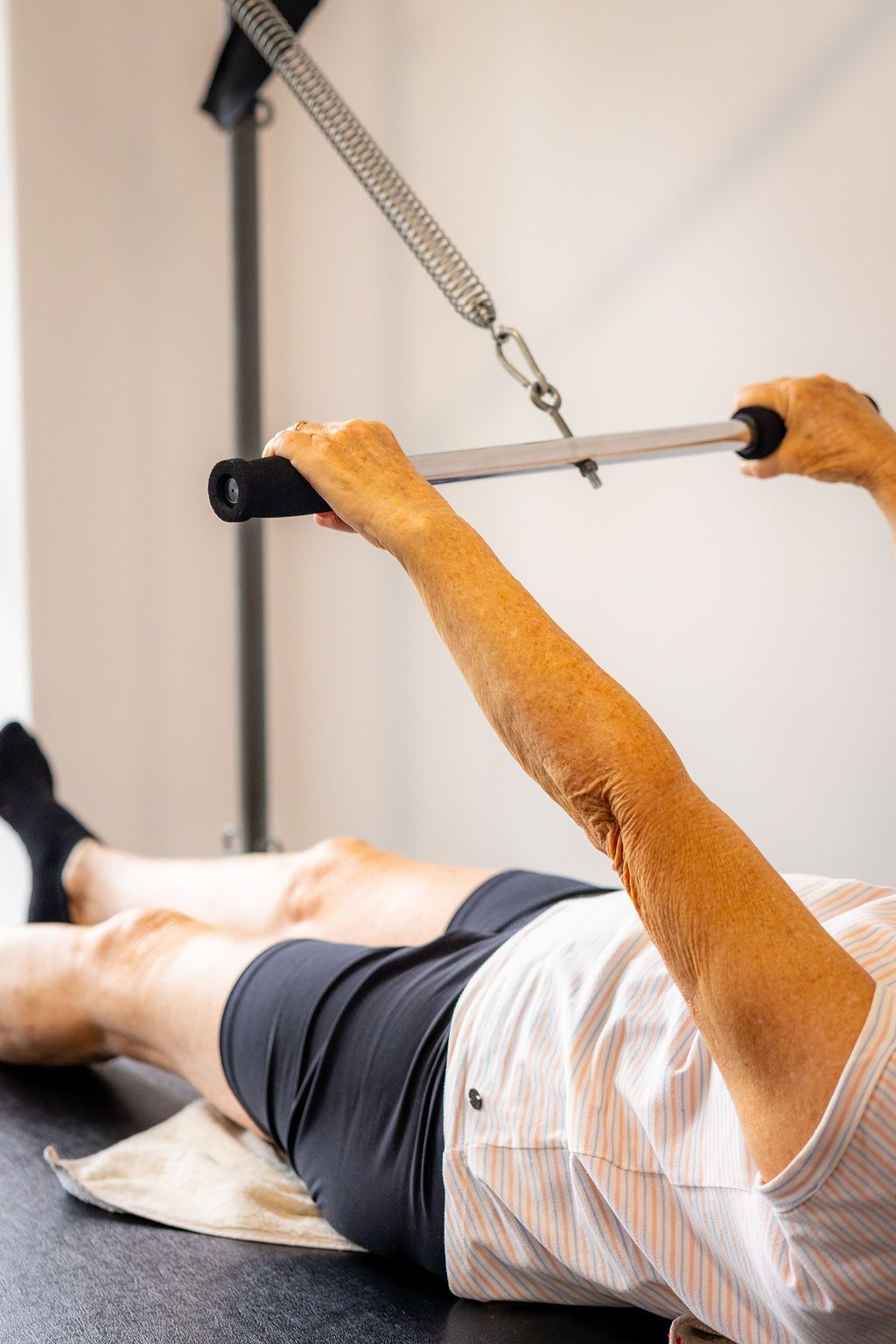 Person using a cable machine during a workout, lying on a bench and pulling a bar down. — Forerunner Physio In Taree, NSW