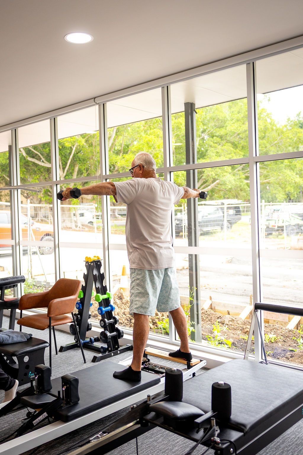 Person exercising on a balance platform, arms outstretched, in a bright gym with large windows.   — Forerunner Physio In Taree, NSW
