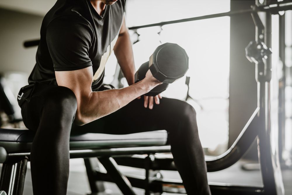 Man Lifting Dumbbell in a Gym, Seated on a Bench — Forerunner Physio In Taree, NSW