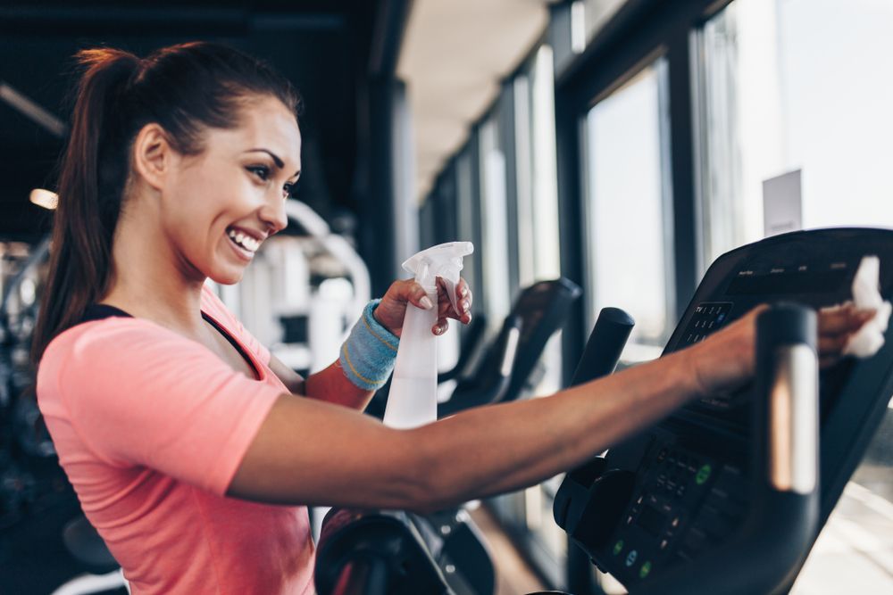 Woman Wiping Down Exercise Equipment at the Gym — Forerunner Physio In Taree, NSW