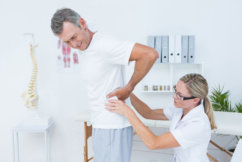 A Healthcare Provider Examining a Patient's Lower Back — Forerunner Physio In Taree, NSW