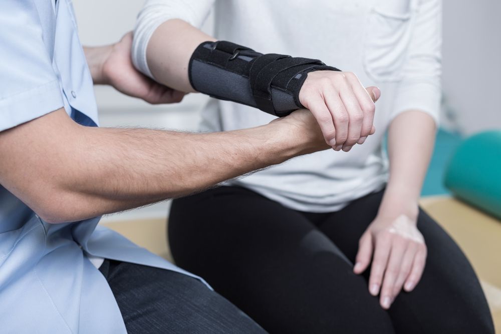 Therapist Examining Patient's Wrist in a Brace — Forerunner Physio In Taree, NSW