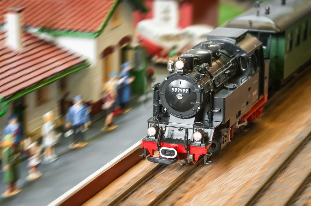 Model Train Pulling Into A Miniature Station With Blurry Figures — Midtown Hobbies In Lismore, NSW