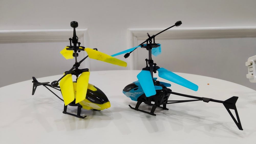 Two toy helicopters: yellow and blue, on a white table — Midtown Hobbies In Lismore, NSW