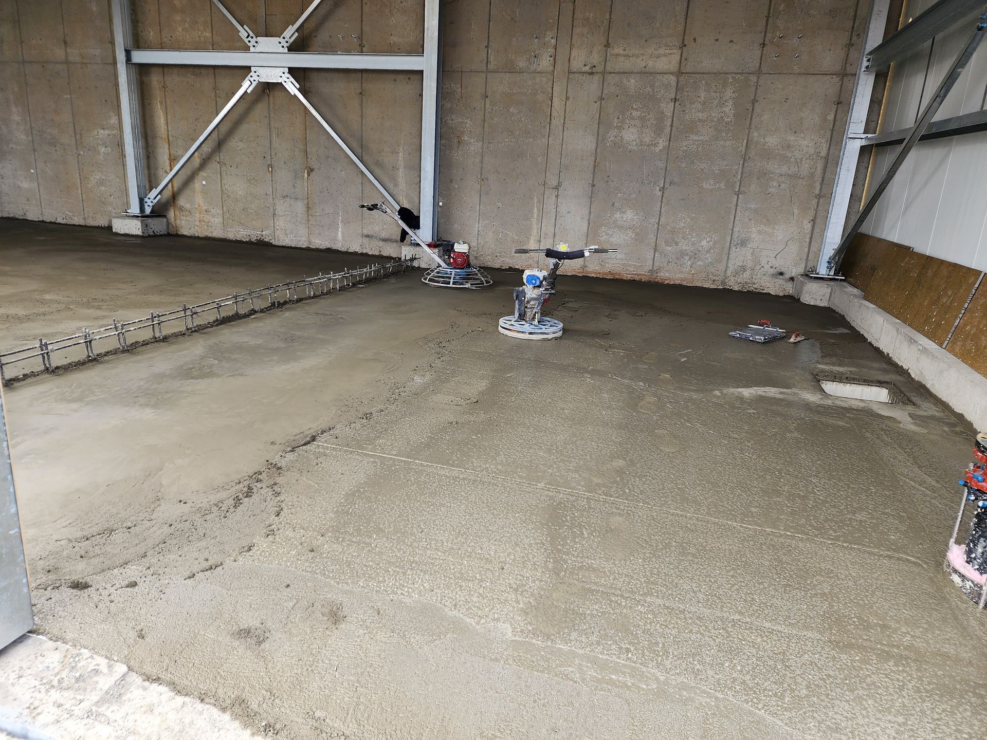 Une personne utilise une machine pour niveler un sol en béton dans un bâtiment.