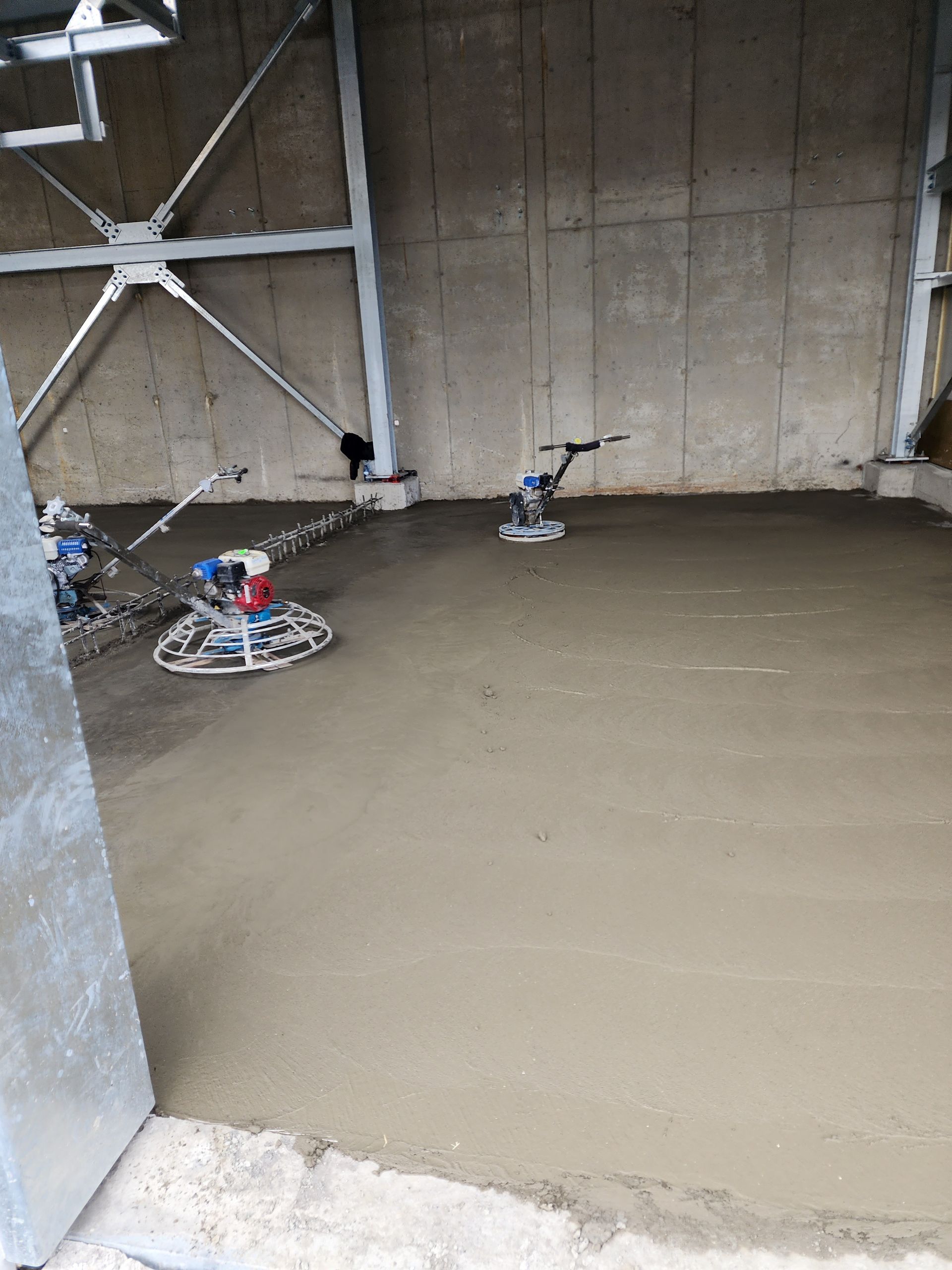 Un sol en béton est en cours de finition dans un bâtiment.