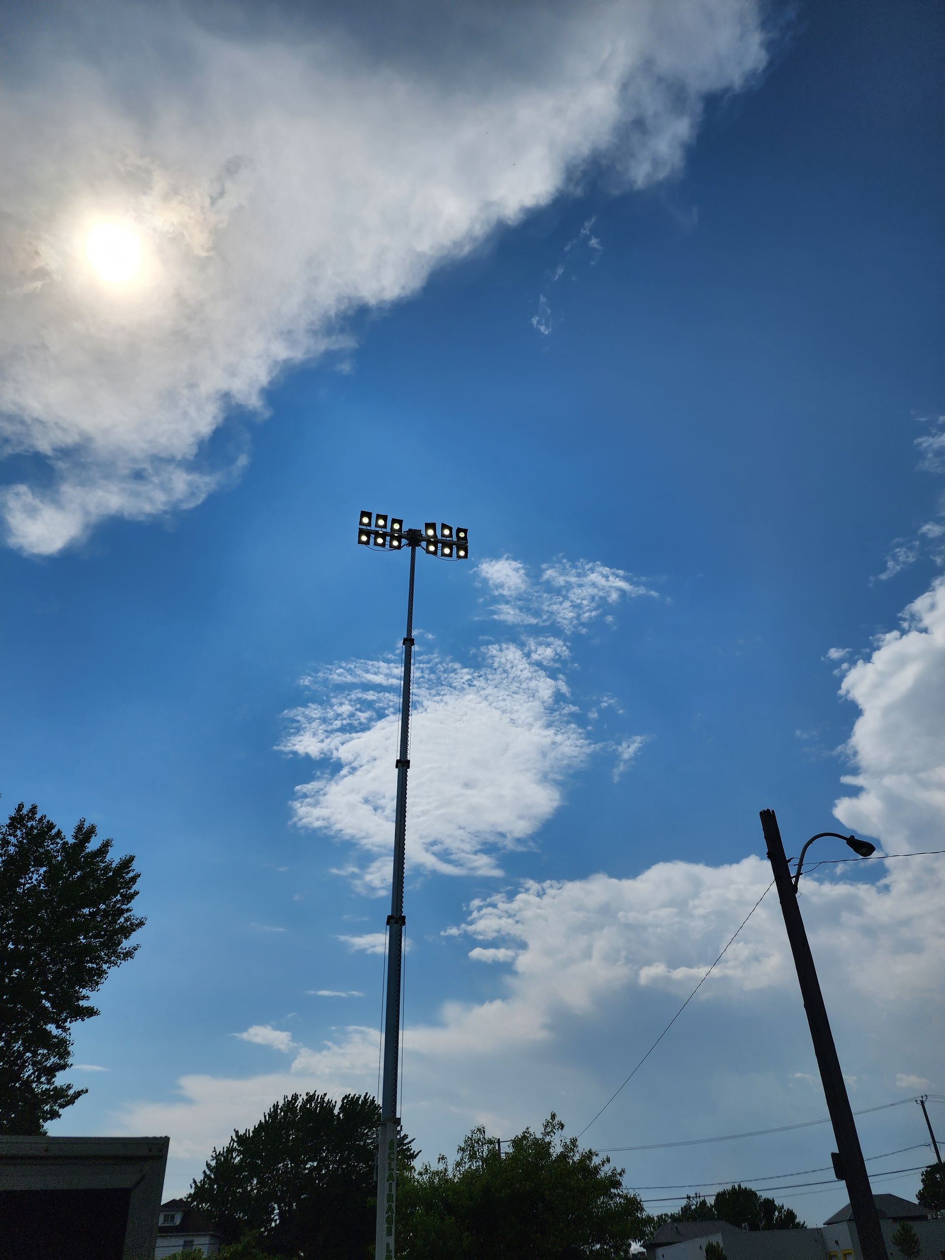 Une lumière de terrain de baseball contre un ciel bleu avec des nuages