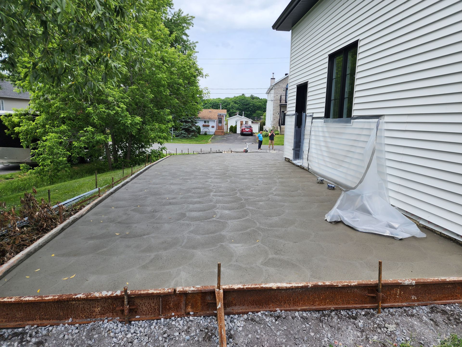 Une allée en béton est en cours de construction devant une maison.