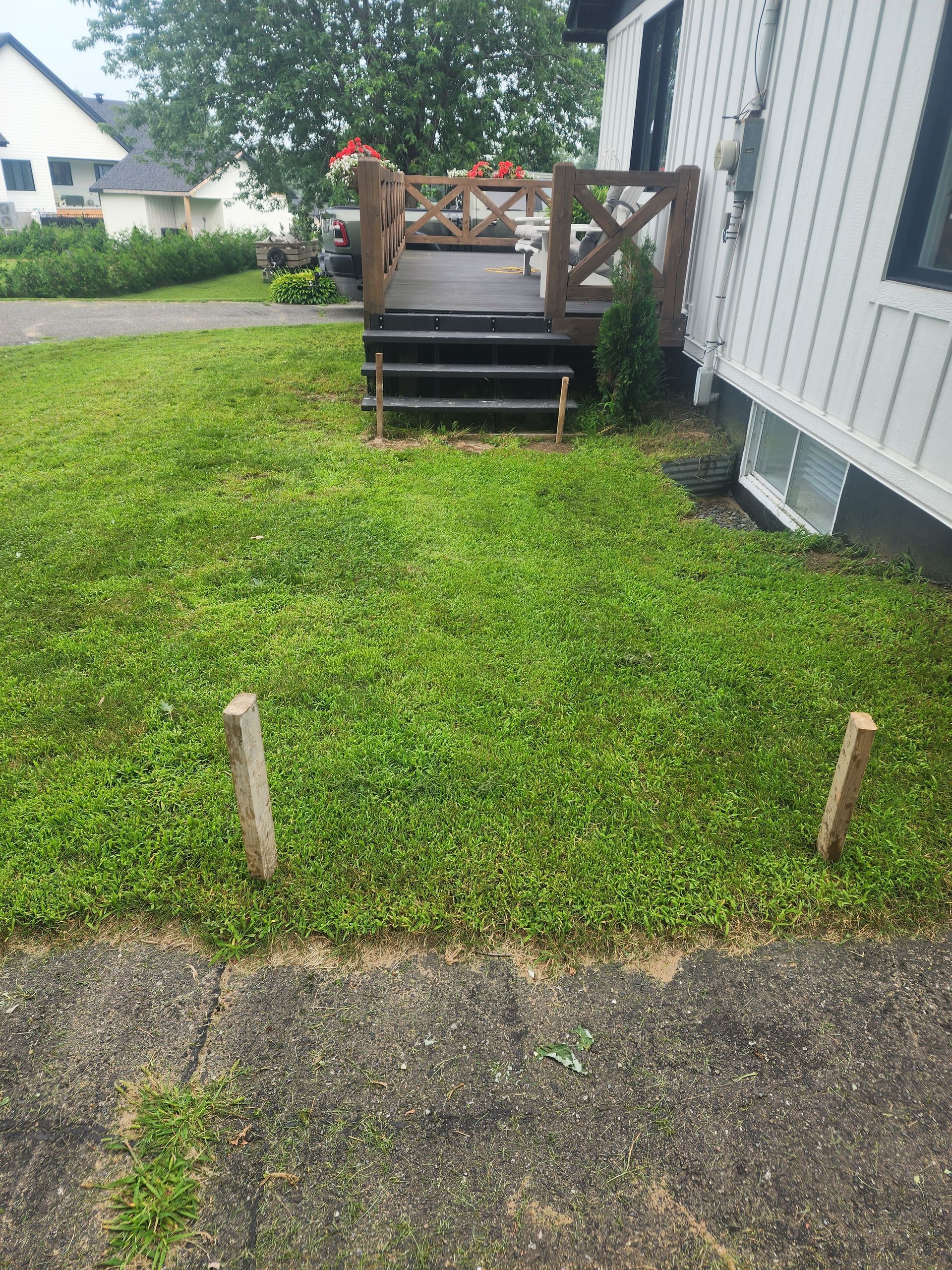 Une pelouse avec une terrasse et des escaliers devant une maison.