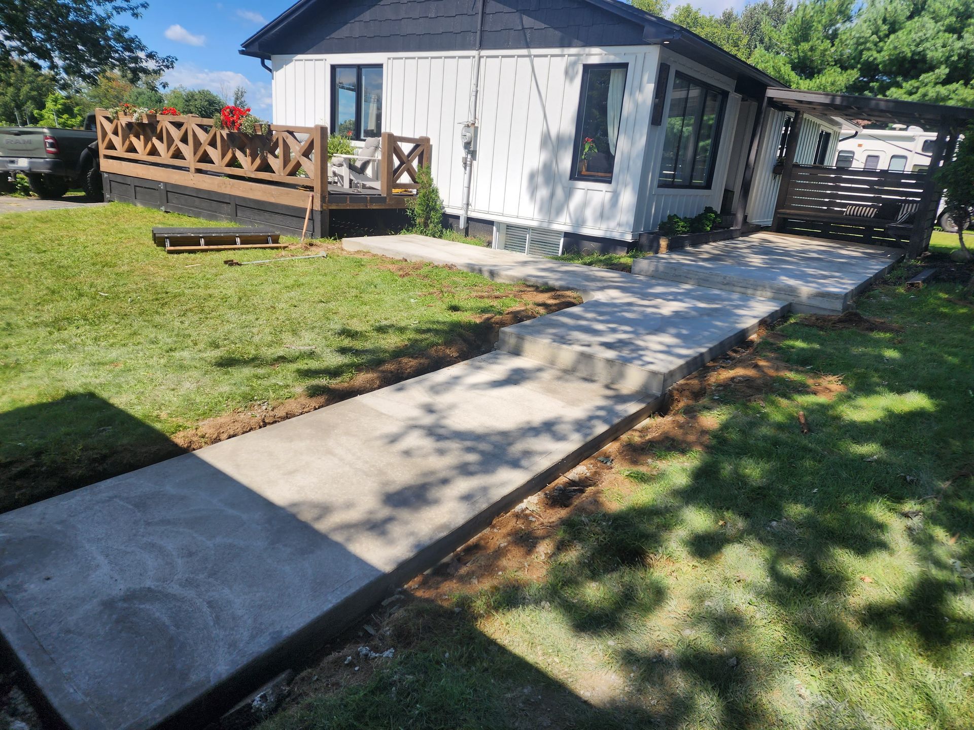 Une maison blanche avec une passerelle en béton qui y mène.