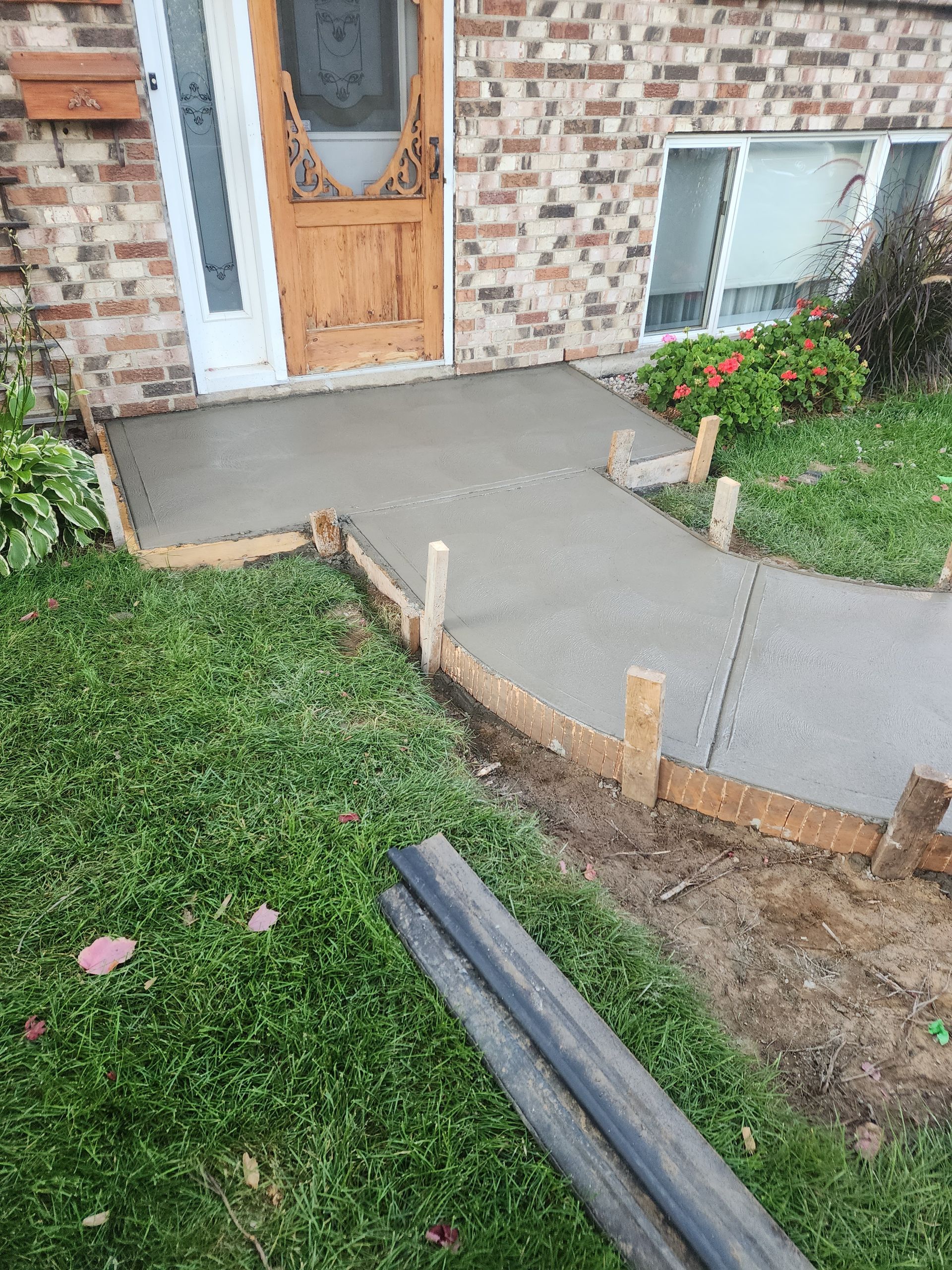 Une passerelle en béton est en cours de construction devant une maison en briques.