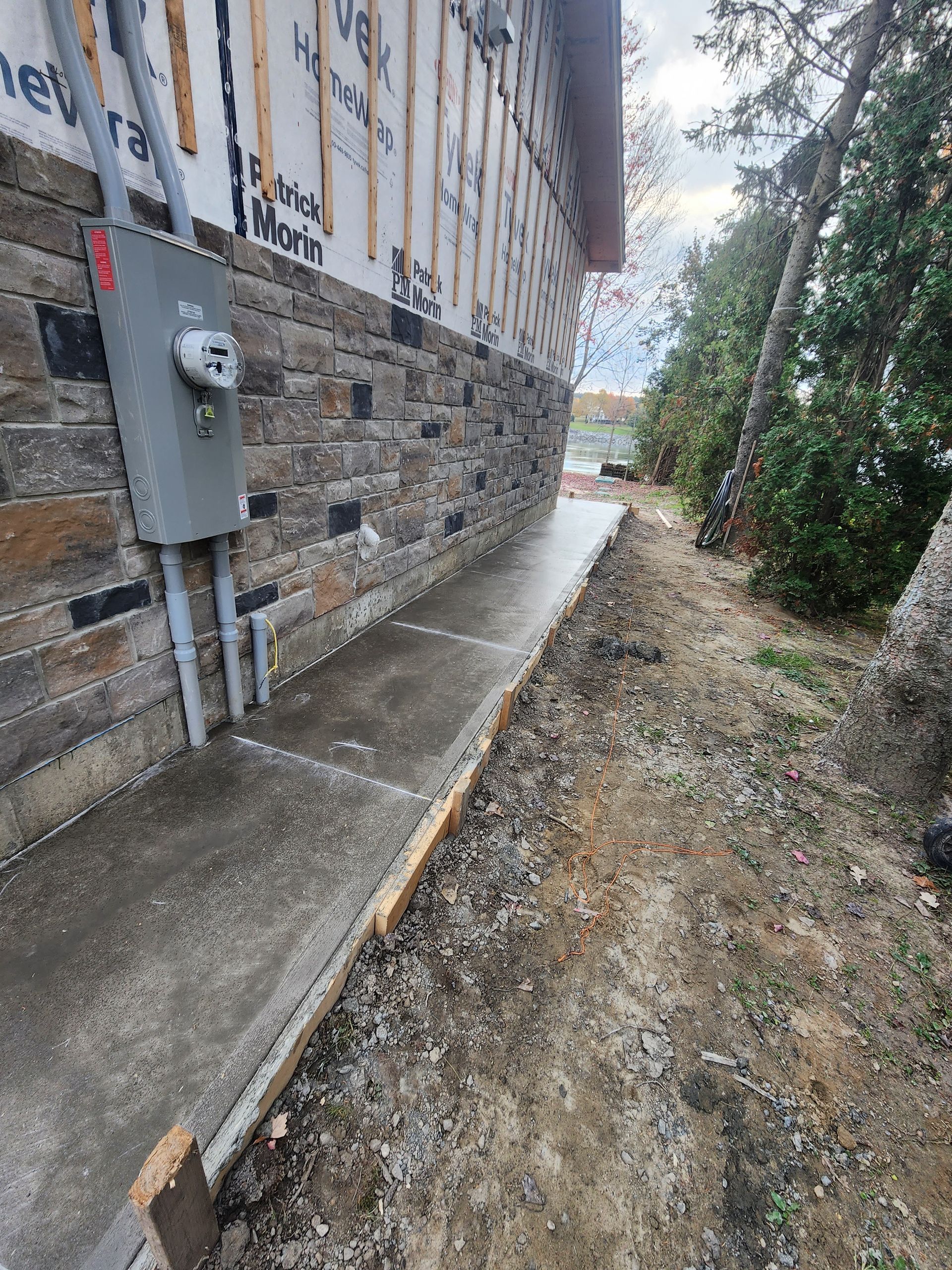 Un trottoir est en cours de construction à côté d'un mur de briques.