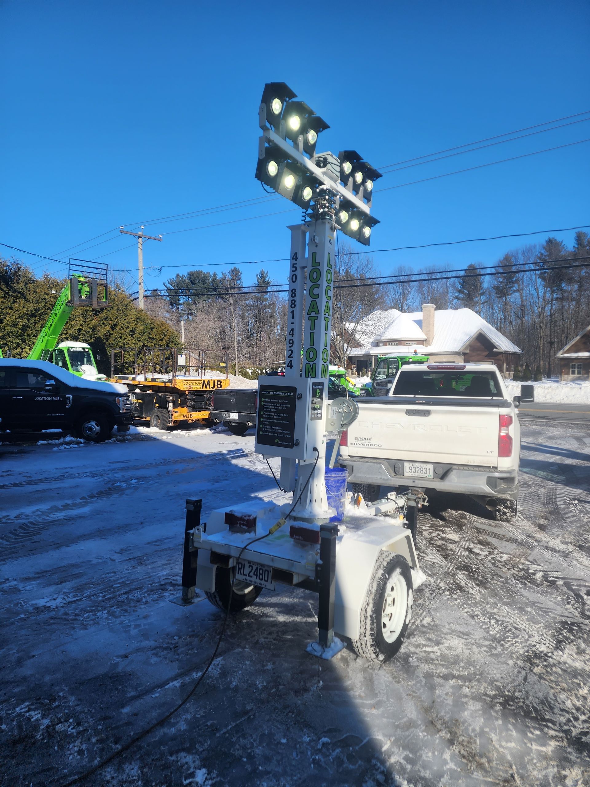 Un camion est garé dans la neige à côté d'une remorque avec des lumières allumées.