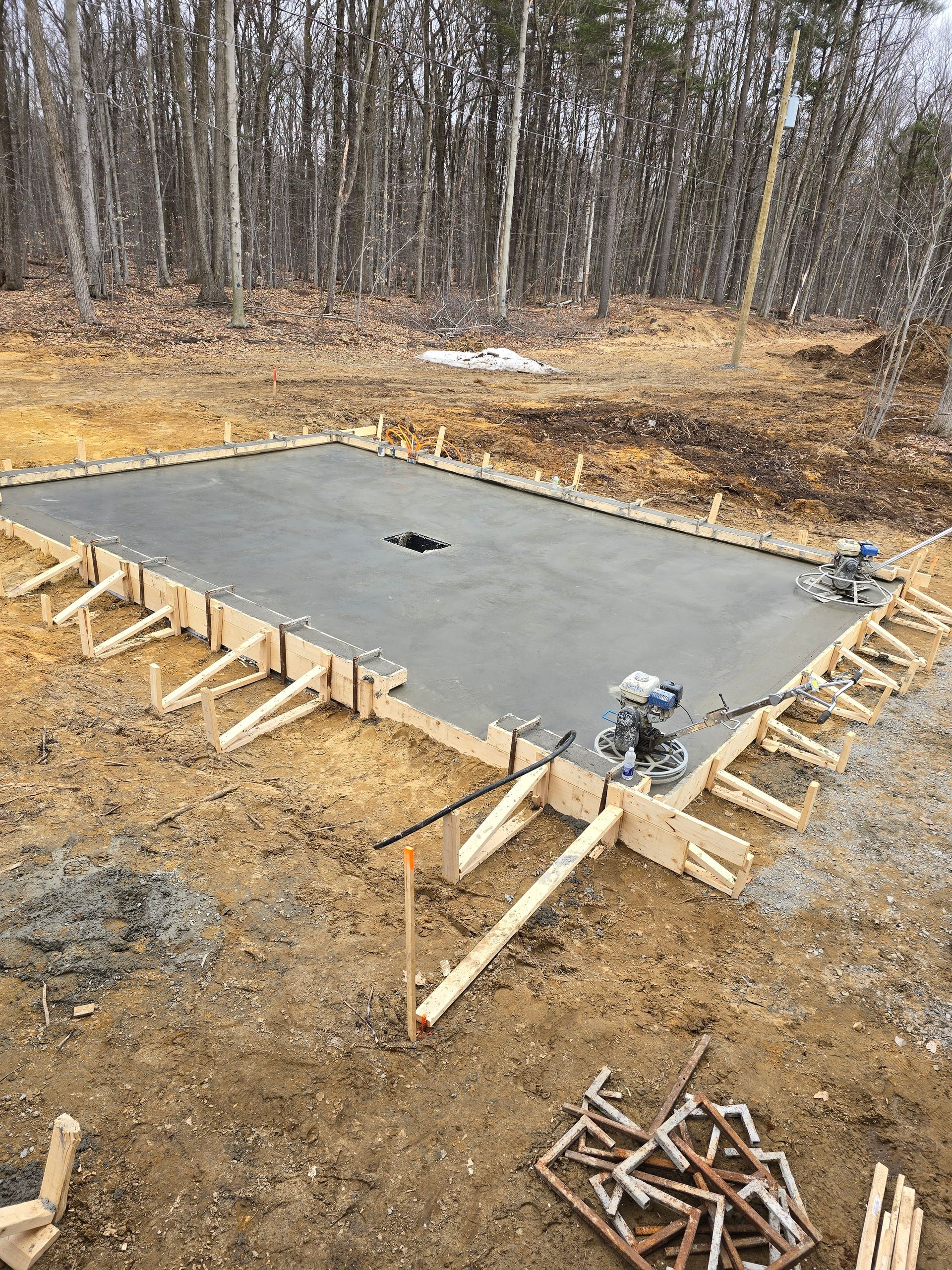 Une grande dalle de béton est en cours de construction au milieu d'un champ de terre.