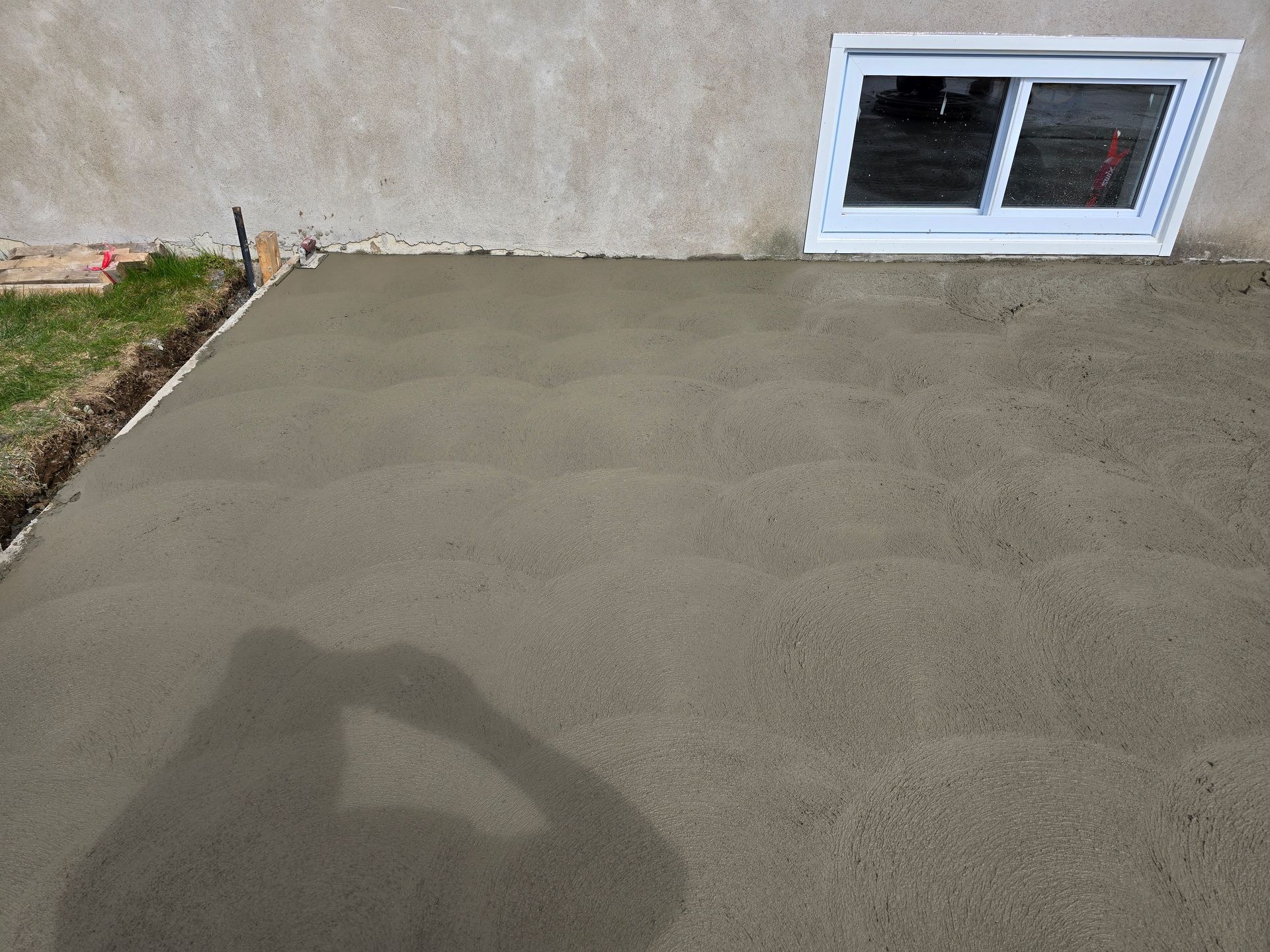 L'ombre d'une personne est projetée sur une surface en béton à côté d'une fenêtre.