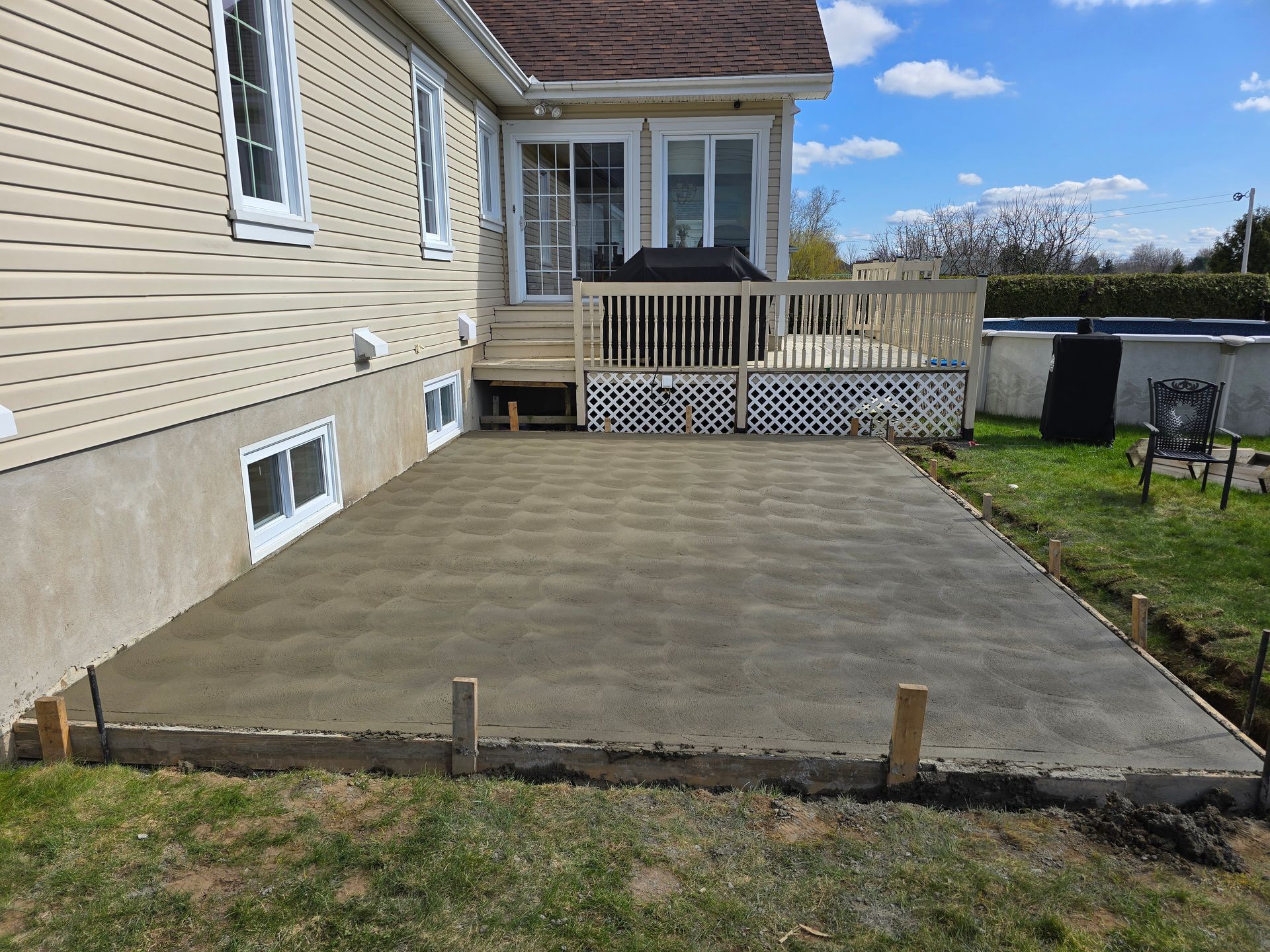 Un patio en béton est en cours de construction devant une maison.