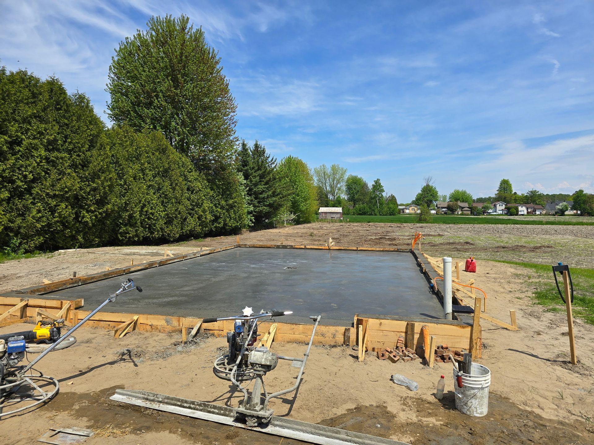 Une dalle de béton est en cours de construction dans un champ de terre.