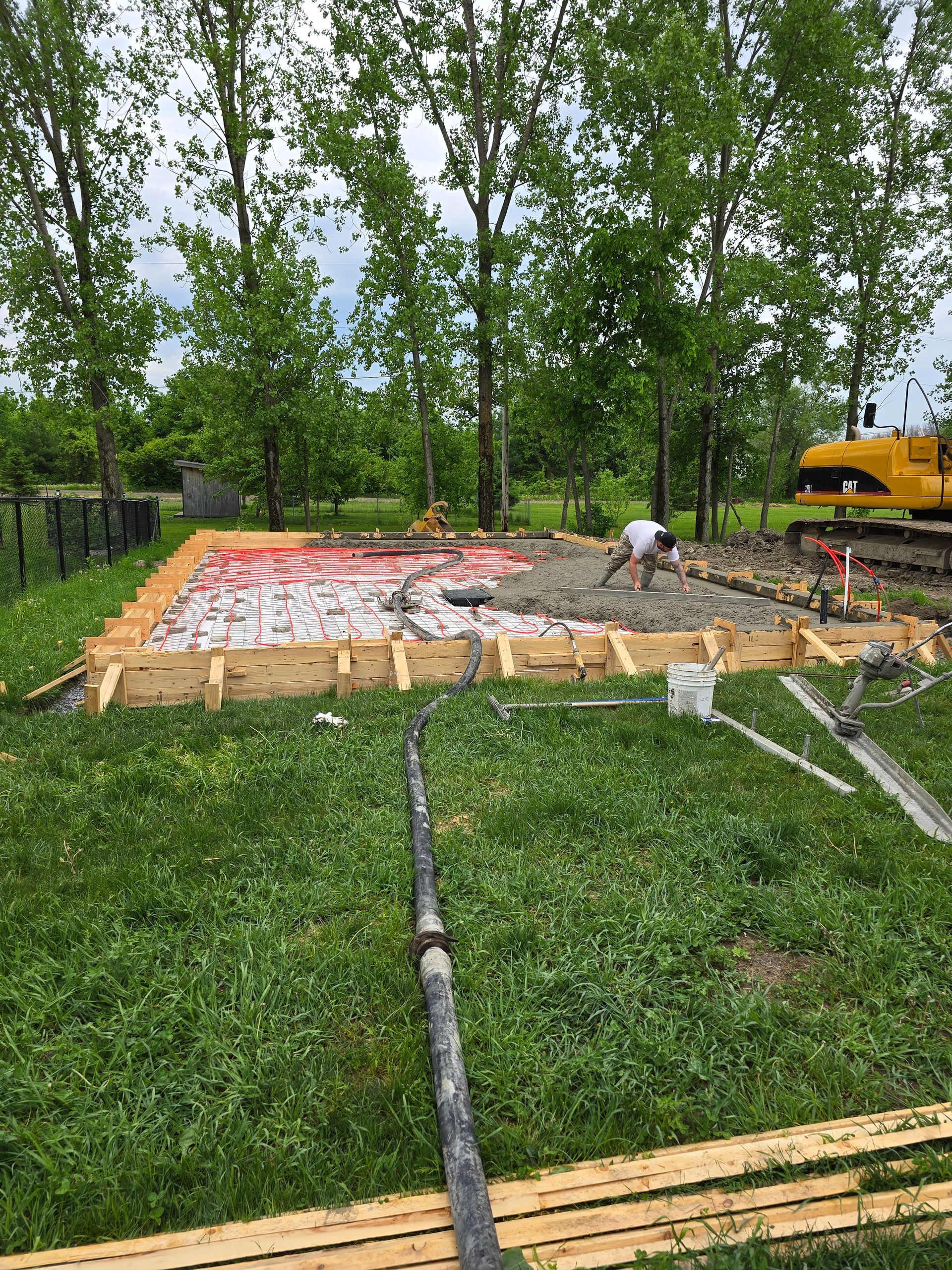Un homme travaille sur une fondation en béton dans une cour.