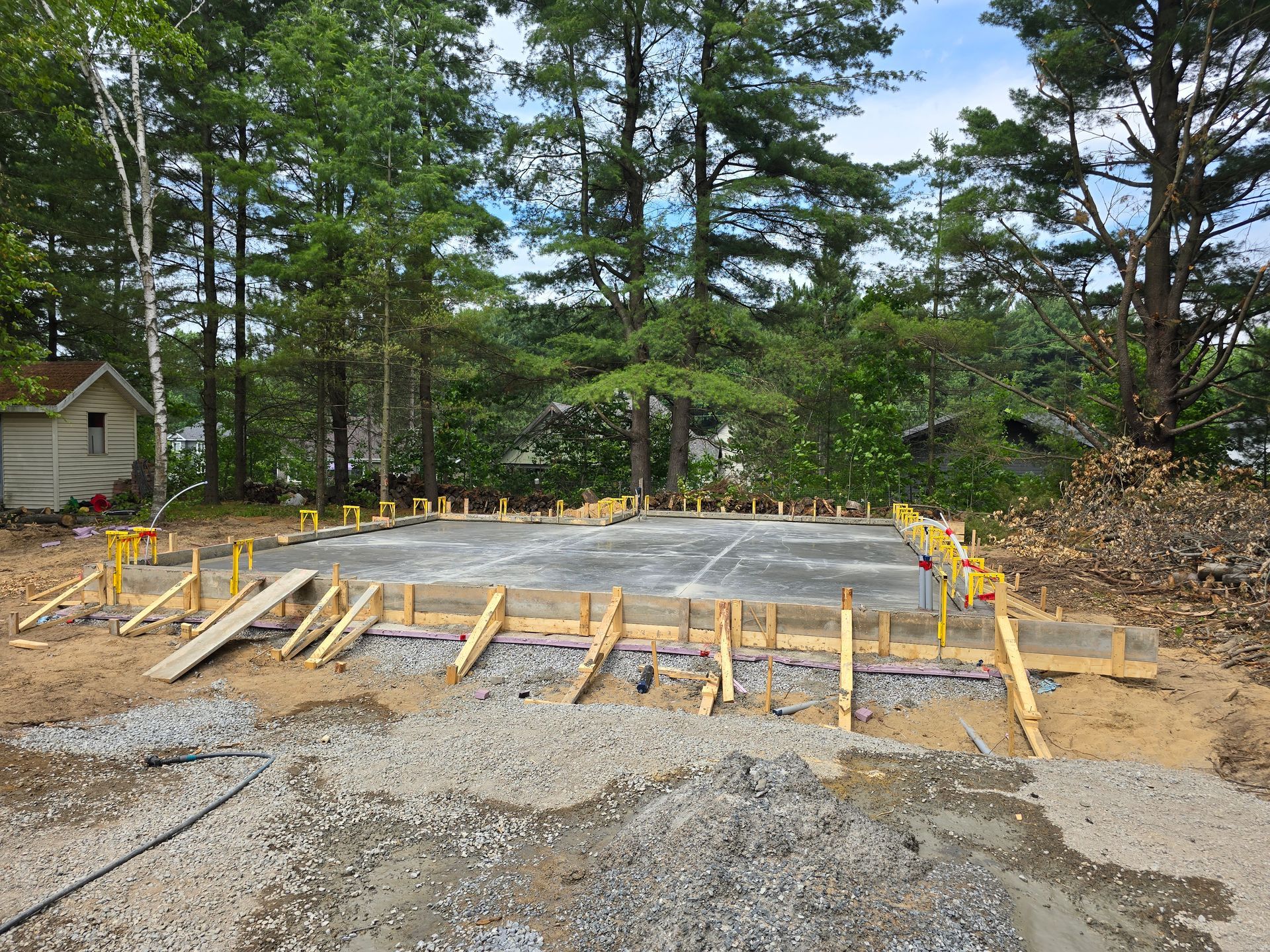 Une base en béton pour une maison est en cours de construction au milieu d'une forêt.