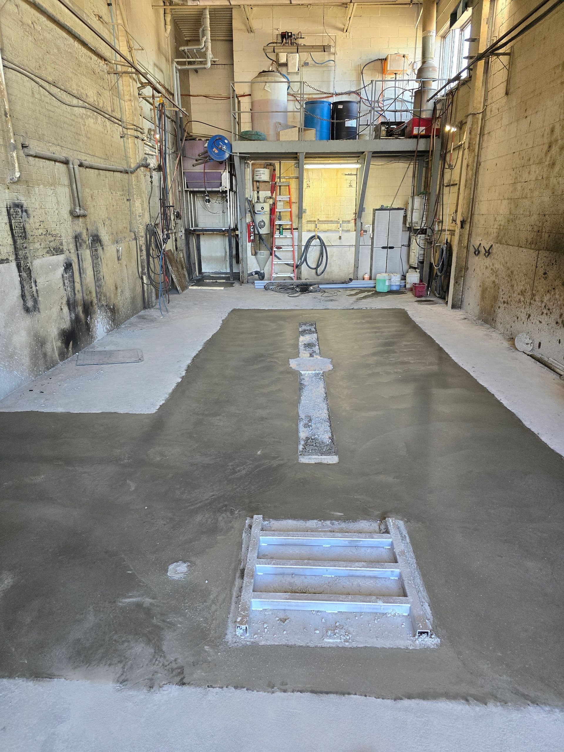 Un sol en béton dans un garage avec un couvercle de regard au milieu.