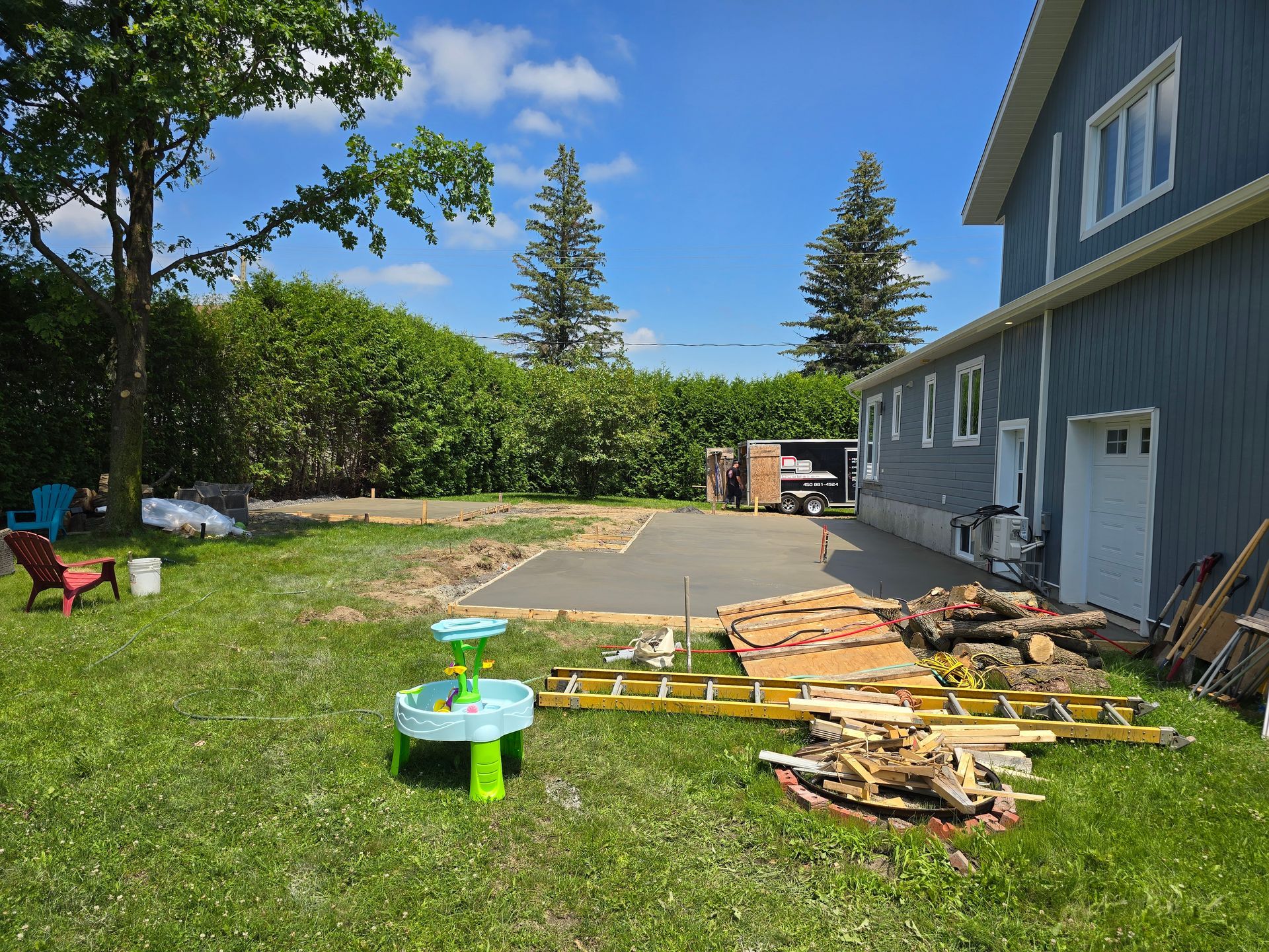 Une cour arrière avec une table à eau et une échelle devant une maison.