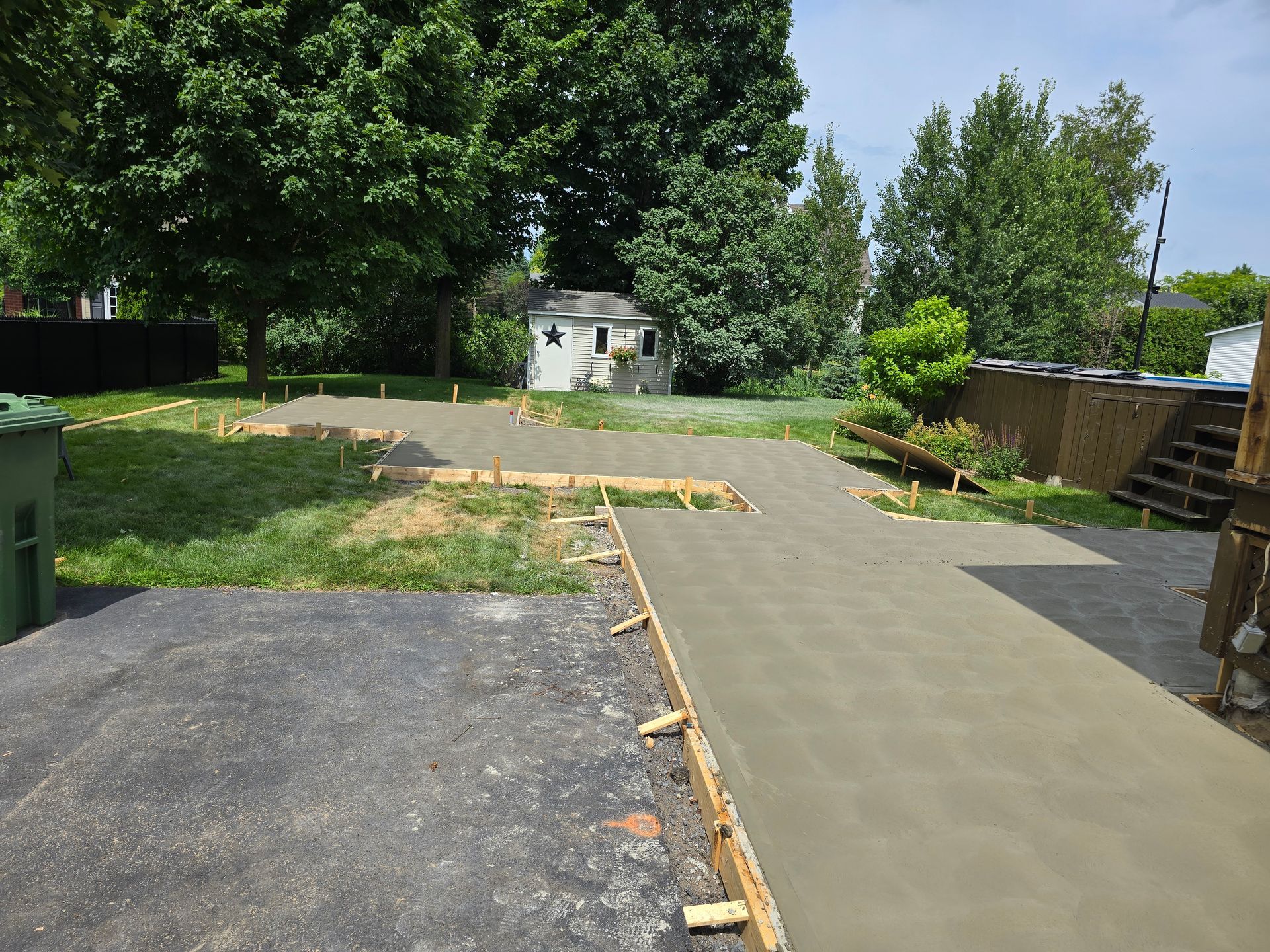 Une allée en béton est en cours de construction dans une cour arrière.
