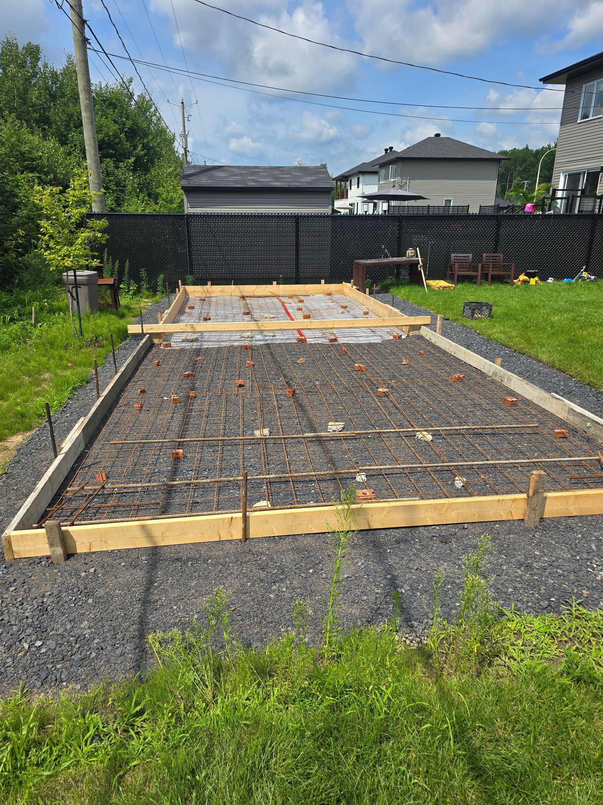 Une base en béton est en cours de construction dans une arrière-cour.
