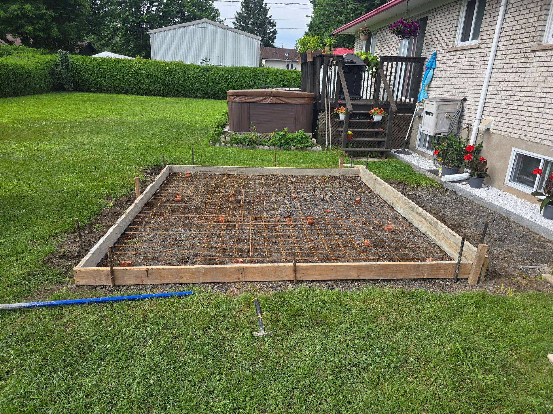 Une dalle de béton est en cours de construction dans l'arrière-cour d'une maison.