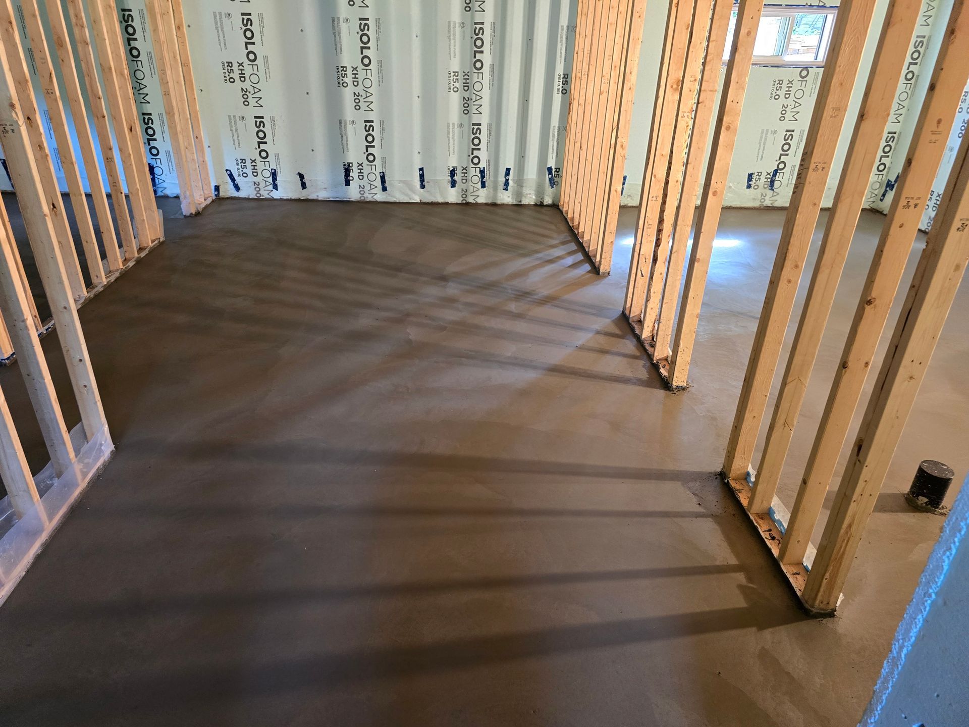 Une pièce avec un sol en béton et des murs en bois en construction.