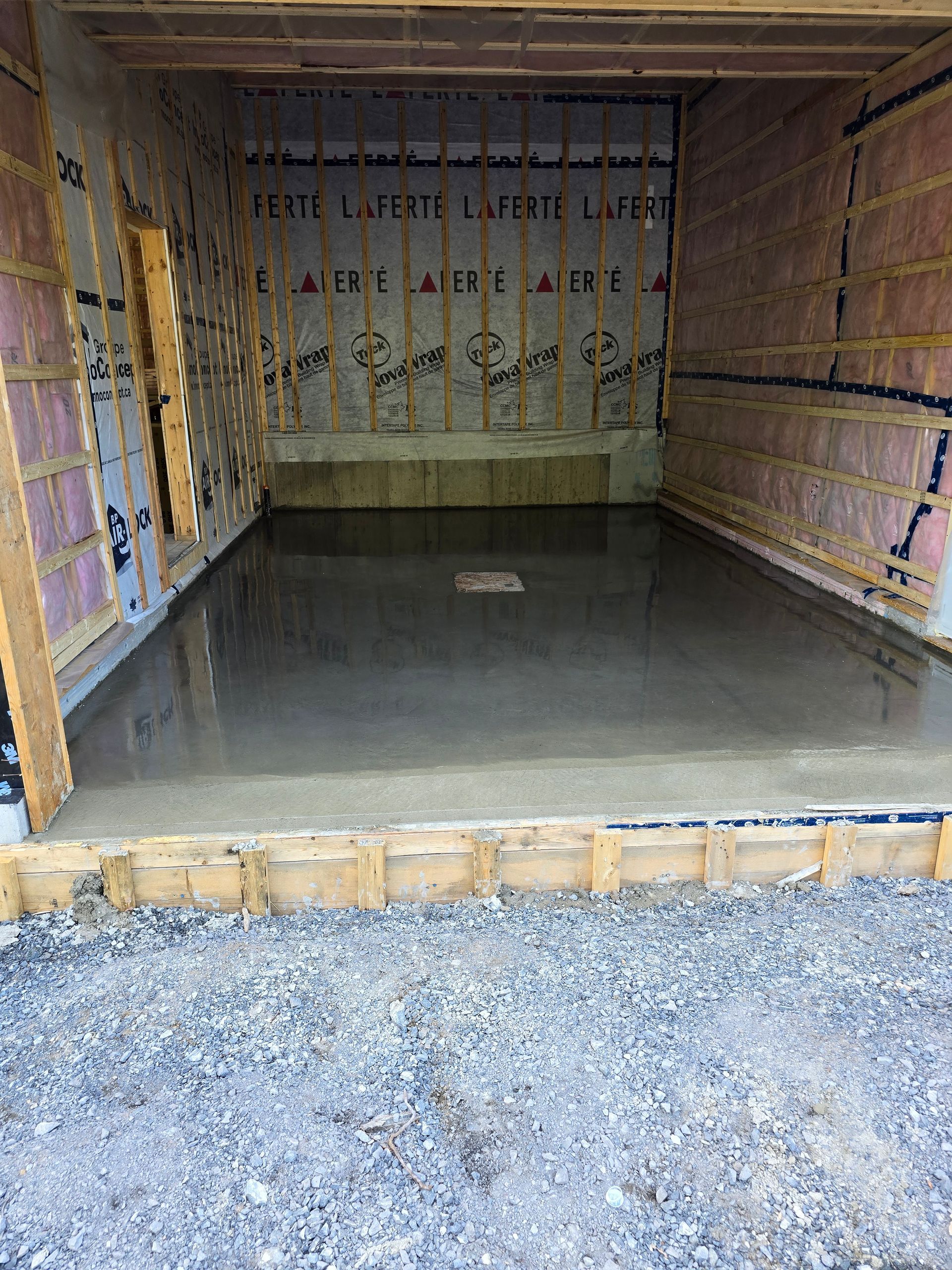 Un plancher en béton est en train d'être coulé dans un garage en construction.