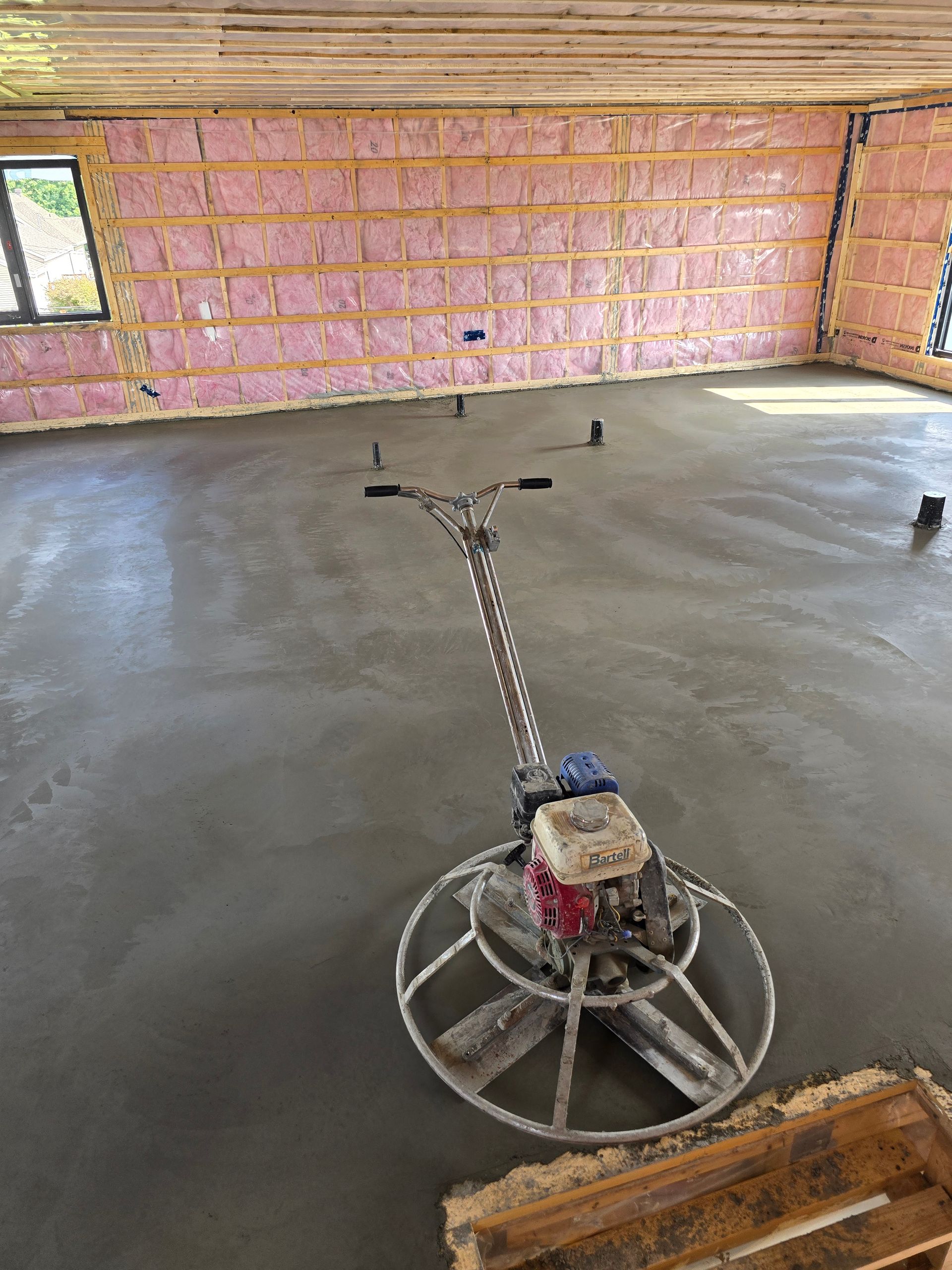 Une finisseuse à béton est utilisée pour finir un sol en béton dans une pièce.